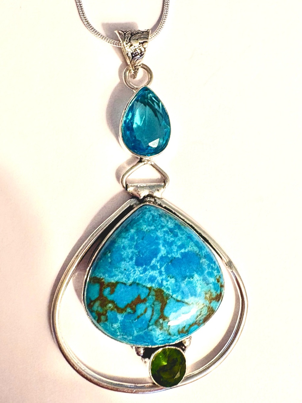 3 inch, 925 marked, hinged, Turquoise, Blue Topaz, Peridot pendant on a chain.